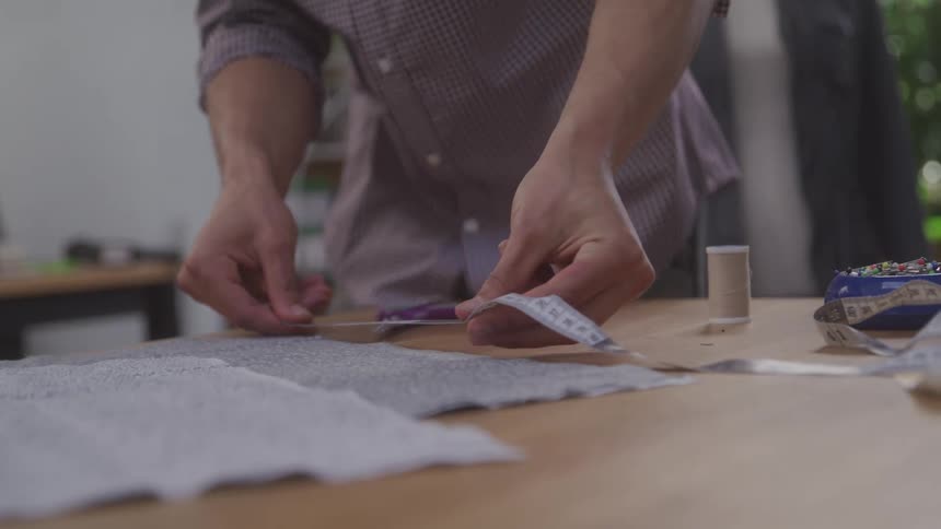 A tailor straightens out a measuring tape