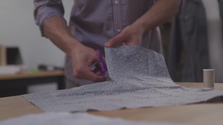 A man is cutting a sheet of fabric