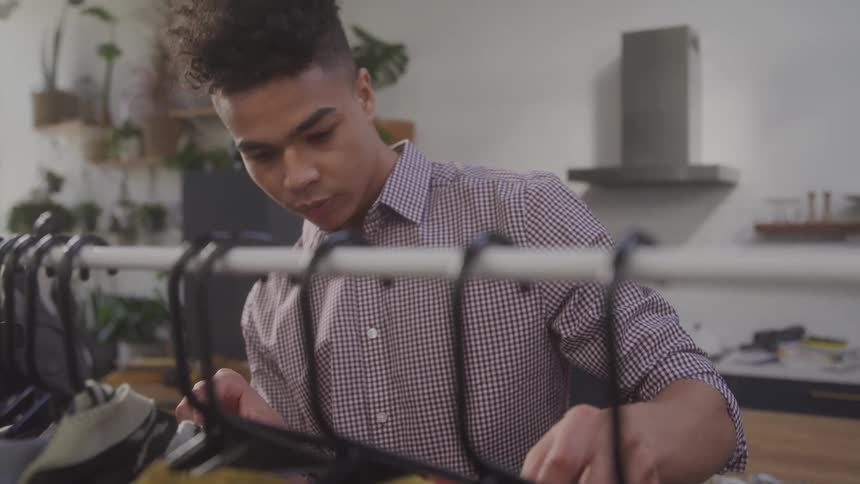 Man looking at clothes on display on hangers in an indoor space