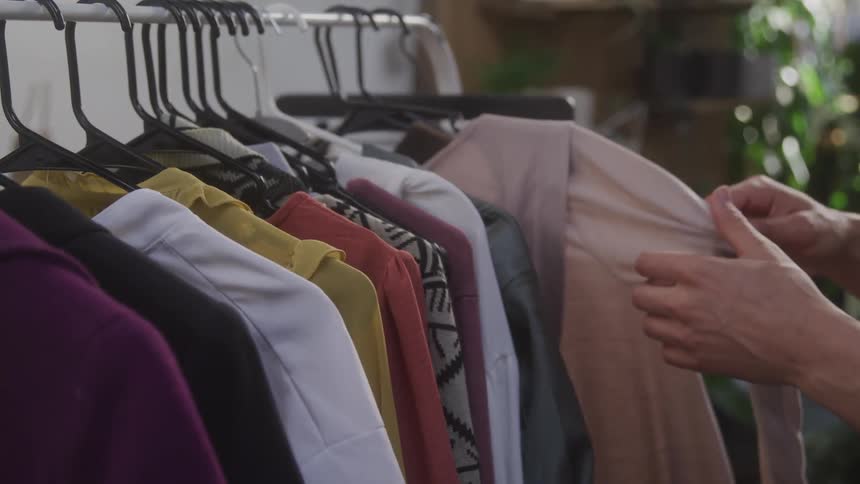 A woman looks through clothes on a rack in a shop
