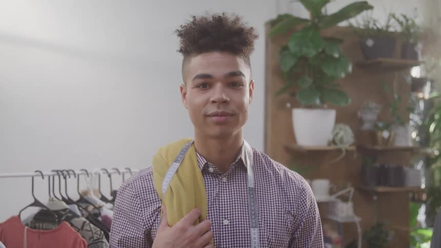 A man is standing with a measuring tape in a clothing store