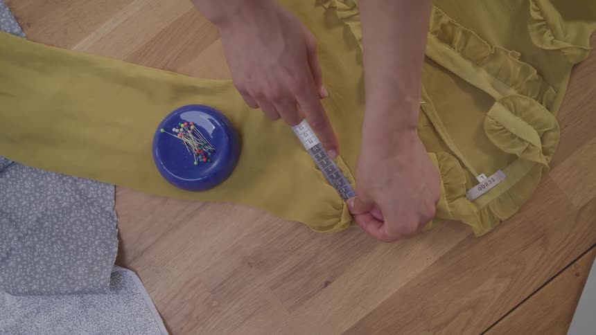 A tailor uses measuring tape to size clothing