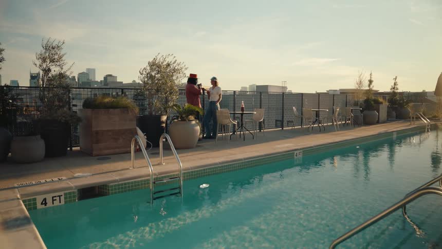 Two people on a terrace by a pool talking