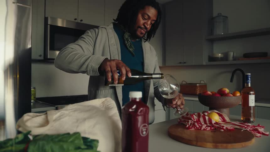 Man taking wine from the fridge and pouring it into a glass