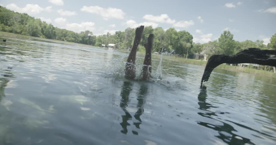 Woman diving into water from a fallen tree branch