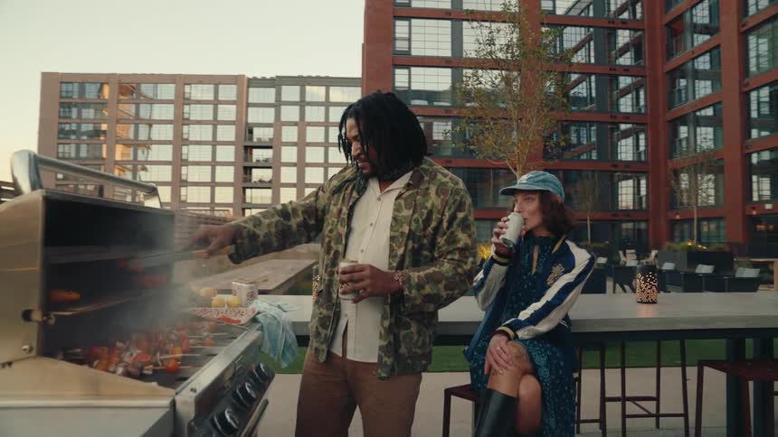 Man and woman having barbecue in an outdoor setting and drinking beer