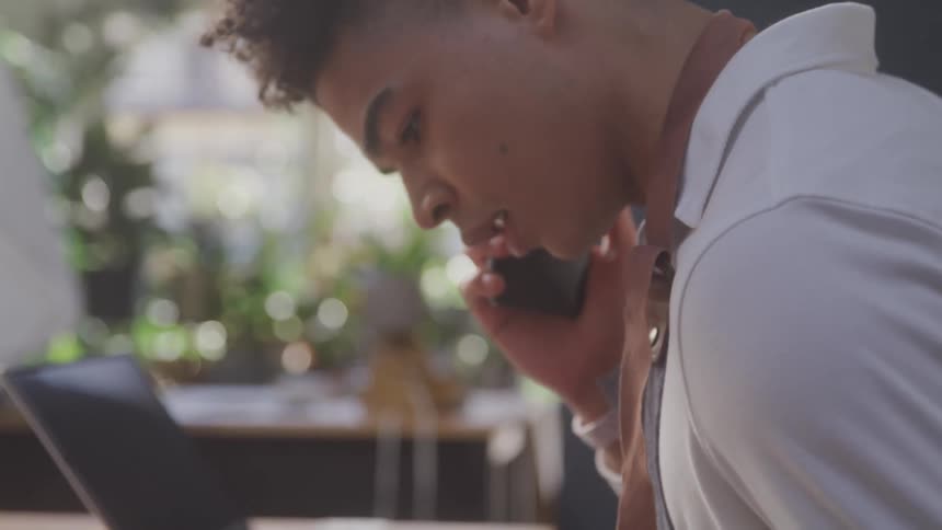 Man working in a plant store talks on the phone