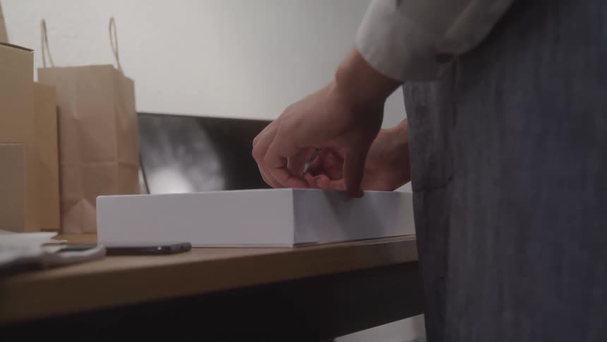 A man is standing with his hands on a box on a table