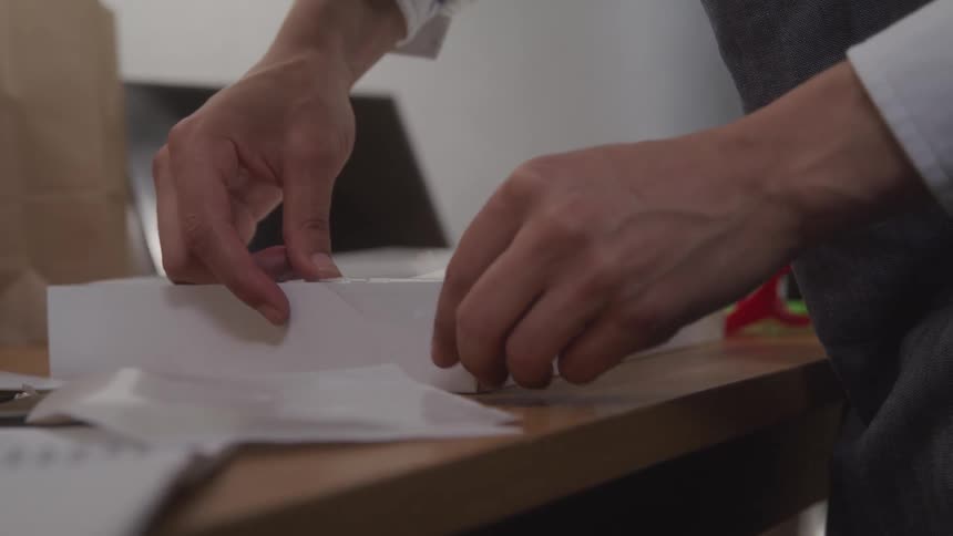 A man is closing a cardboard box on a table