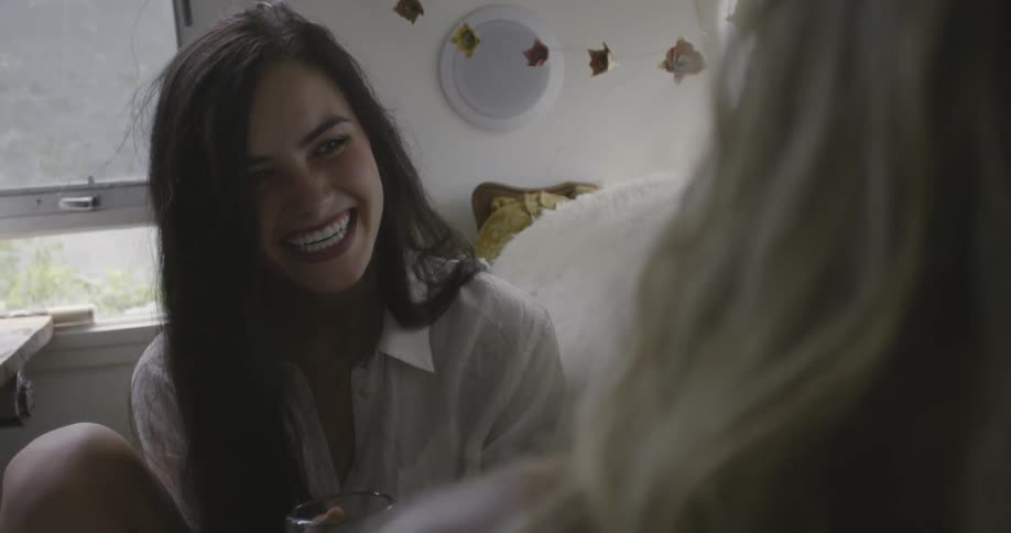 Two women sitting on a couch laughing together