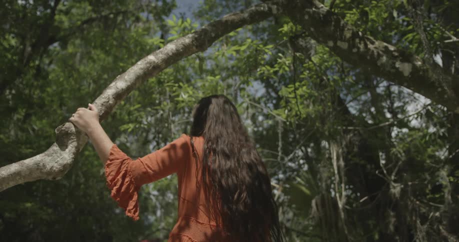 Long-haired woman walking through a wooded area