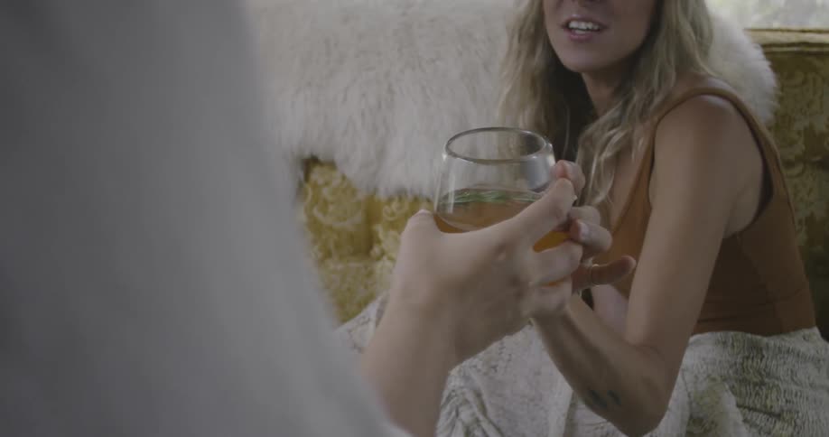 A woman is handing a drink to another woman who is speaking