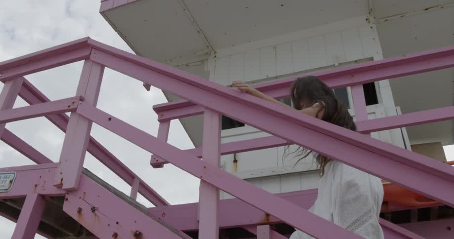 A woman climbs the stairs to a lifeguard tower on a beach
