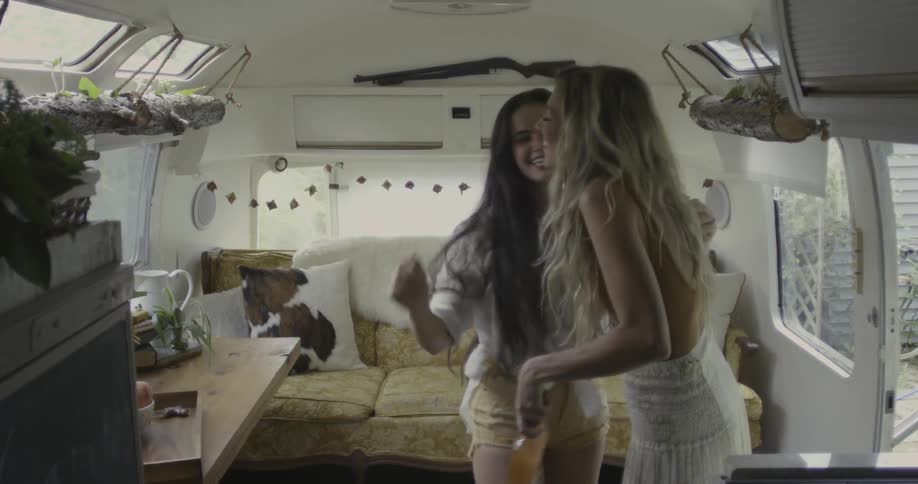Two women greet each other and hug in an rv interior