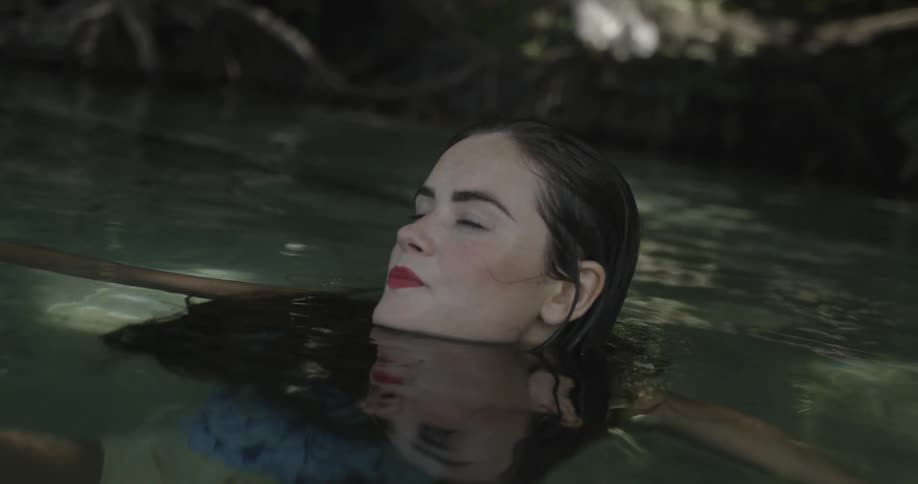 Woman wearing red lipstick swimming in a pond