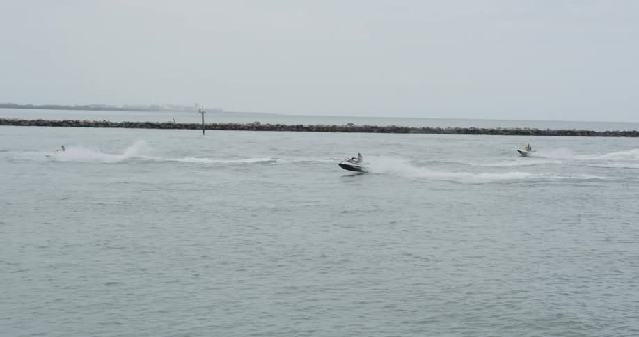 People riding jet skis on a lake on overcast day