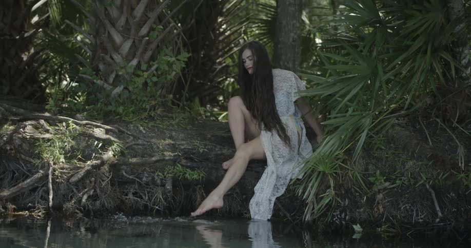 A woman is kicking her toes into a pond