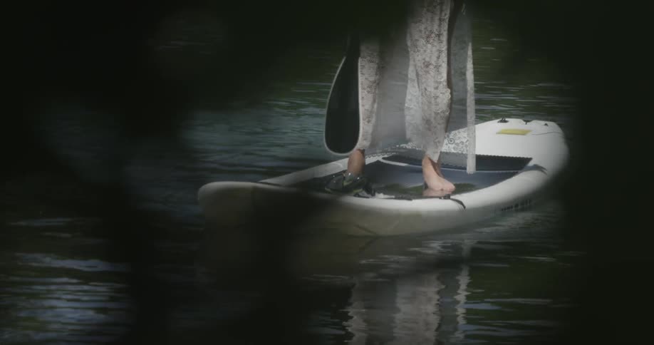 A woman wearing a dress is paddling a stand-up paddle board