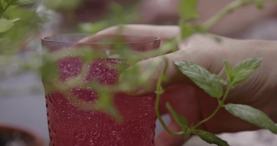 Close up of a hand picking up a glass with liquid in it