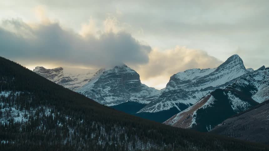 Clouds are moving in over a snowy mountain range