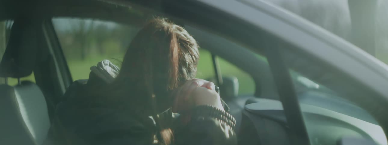 A girl is sitting in the car on a sunny day