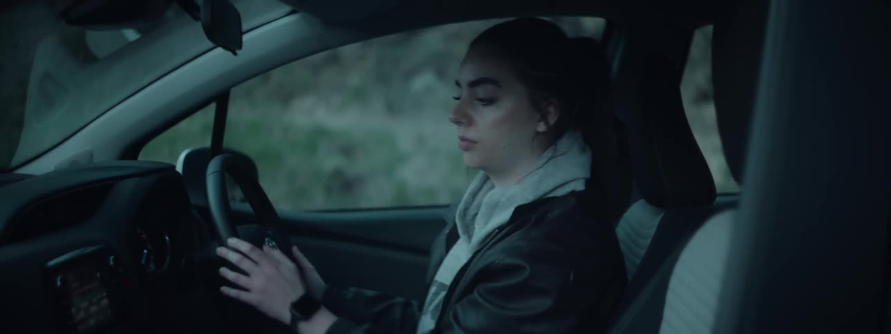 Woman sitting behind the steering wheel of a parked car adjusts the radio
