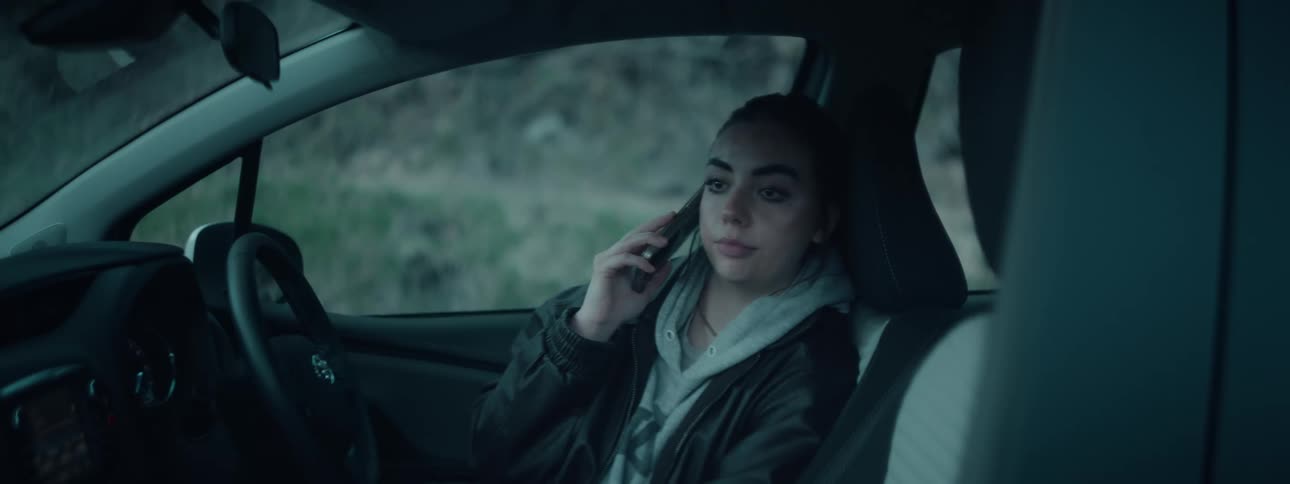 Woman sitting in a parked car talks on her smartphone