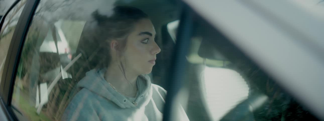 Woman sitting in a stationary vehicle during the day sighs on an autumn day