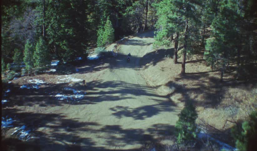 A person rides their dirt bike on the trail