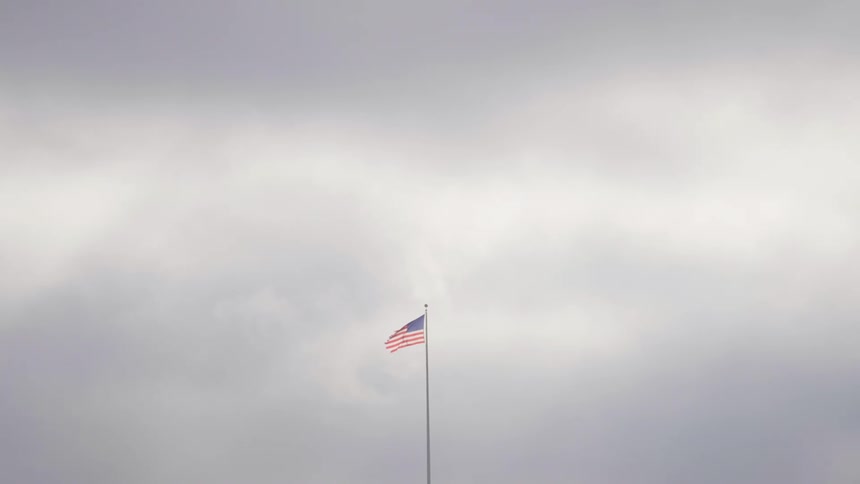 United states flag on a flagpole against a cloudy sky