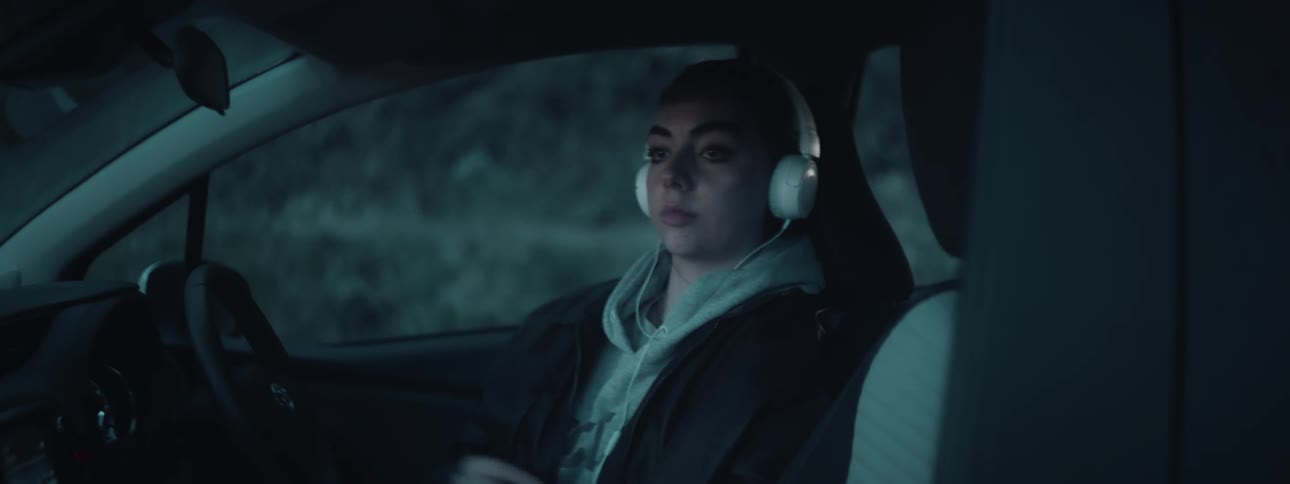 Woman with headphones sitting in a parked car