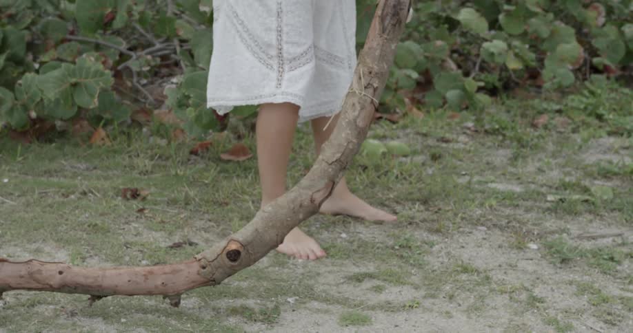 A woman is lifting up and twisting a long tree branch
