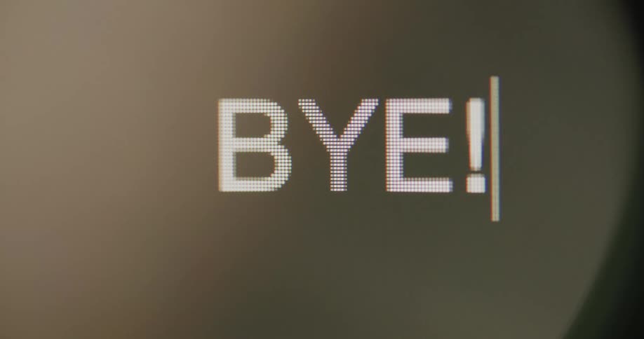 Close up of the word bye being typed in a pixelated white font followed by a blinking cursor on a black screen