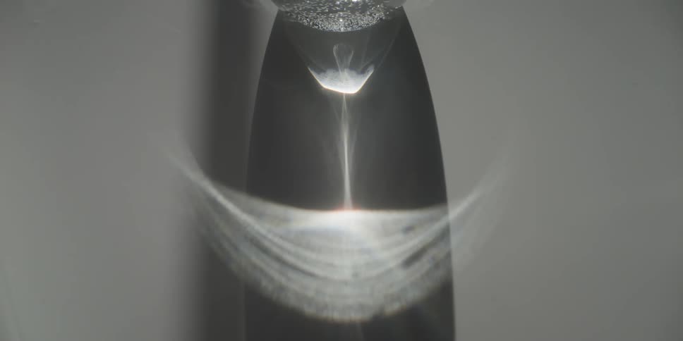 A reflection of liquid moving shows on a glass bottle