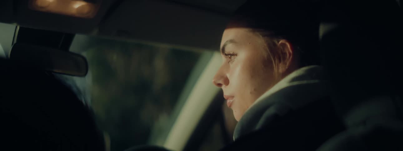 A woman sits in the dark in her car