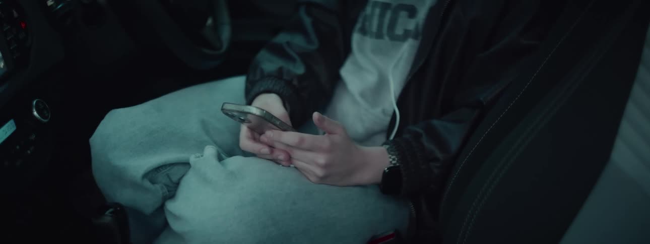 A person sitting down holds a smartphone in their hands texting or scrolling