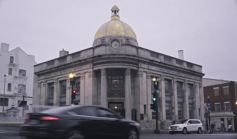 People and traffic moves past a domed building as the day progresses