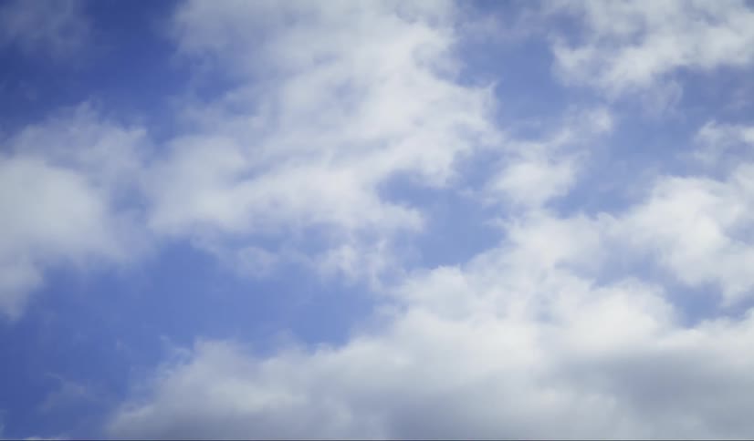 A clear blue sky with fluffy white clouds moving across it