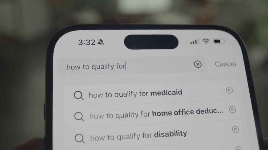 A person is holding a smartphone and typing a loan inquiry into the search bar