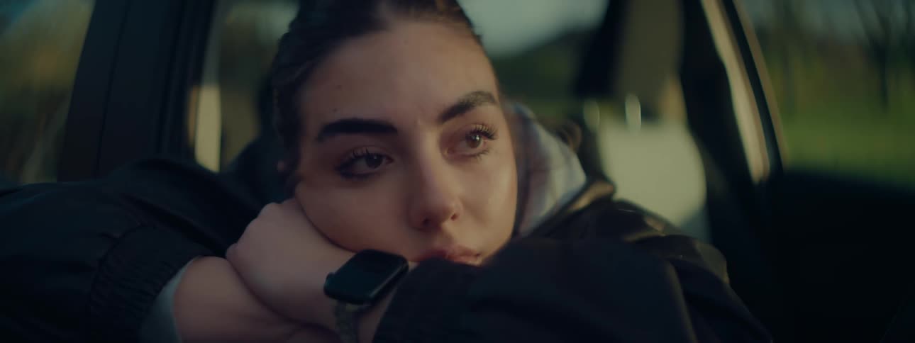 Woman with her arms crossed and her face leaning thoughtfully inside a car