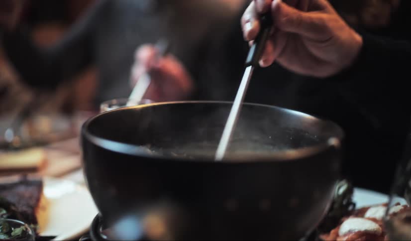Hand handling a spoon in a bowl that exhales steam