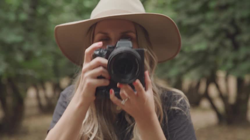 A woman wearing a tan hat is taking a photo using her camera