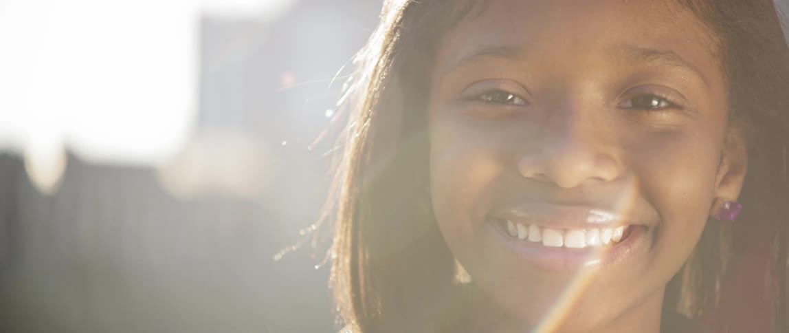 The sun shines down on a smiling girl
