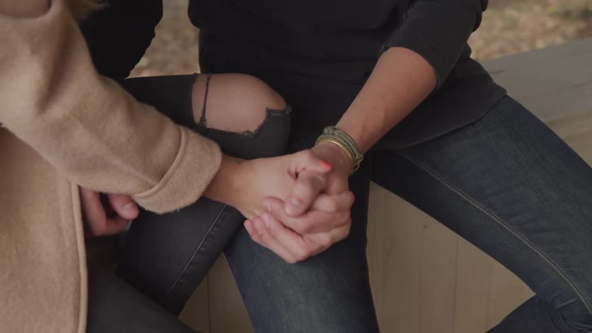 Close up of a couple holding hands while sitting