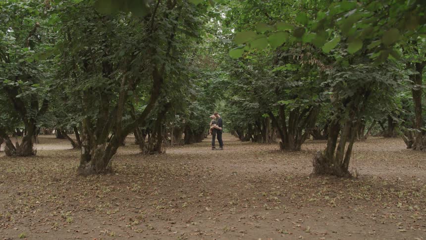 Couple hugging in a field with trees