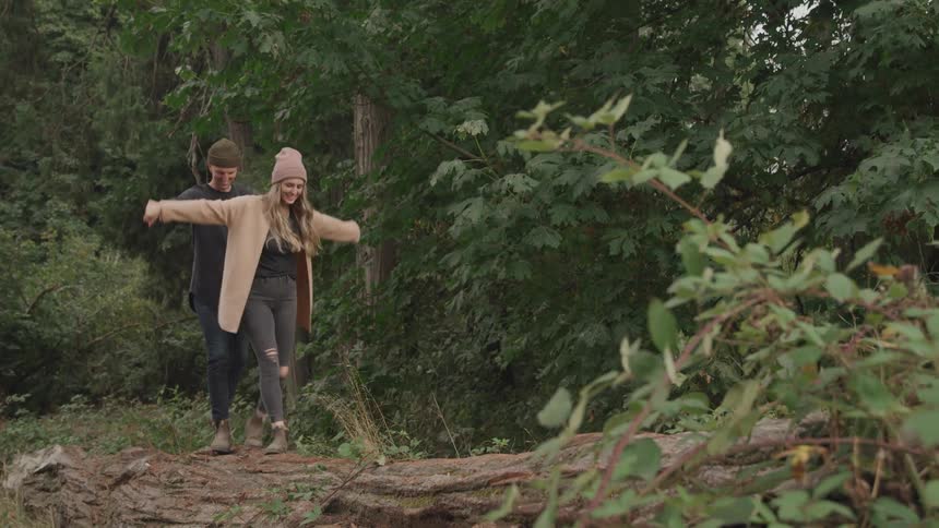 Couple holding hands walking together through a forest
