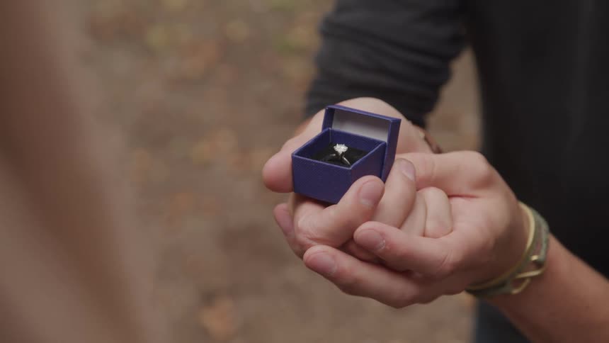 Kneeling man holds a ring to propose marriage