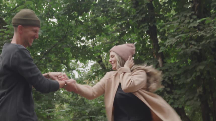 A couple run and dance in a park