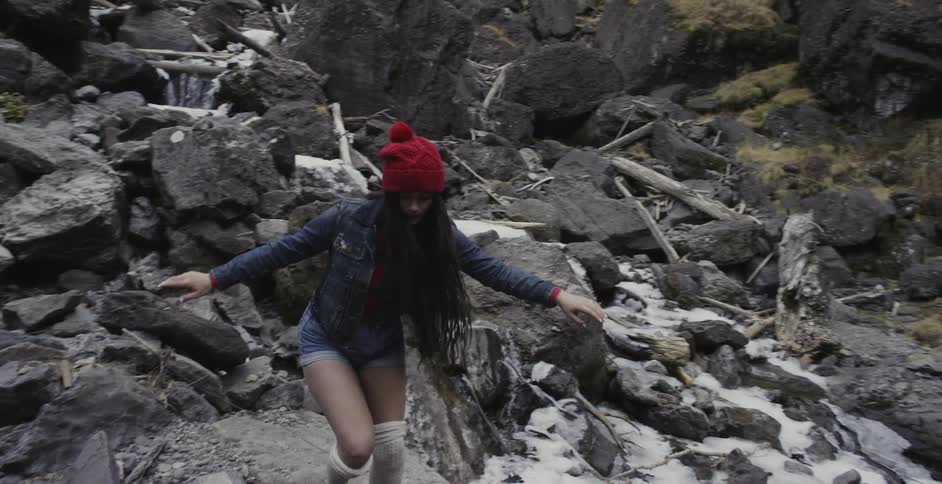 Woman hiking over large rocks near river in forest