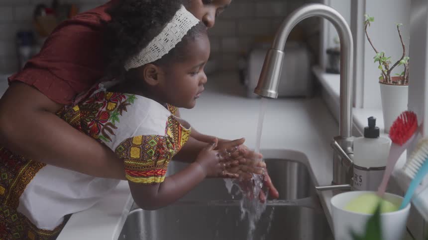 A mother is helping her daughter wash her hands